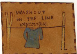 Leather postcard, never mailed. Shows a washline with a blue shirt hung on it. Message says: Washout On The Line Vancouver.